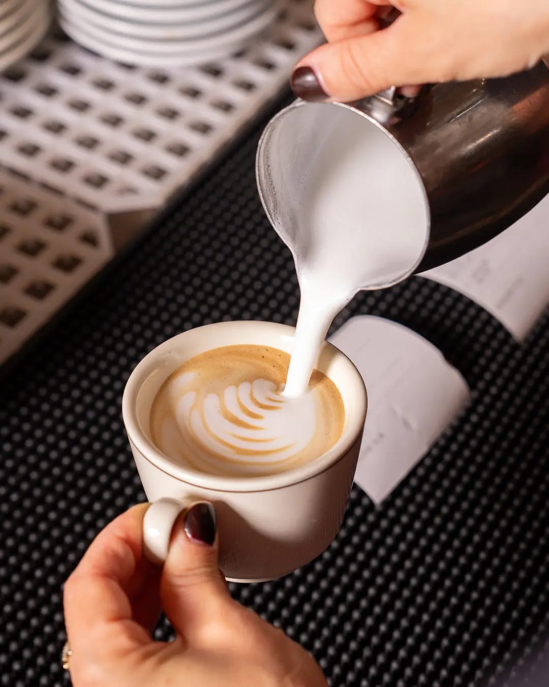Barista prepara un cappuccino con latte art al bancone