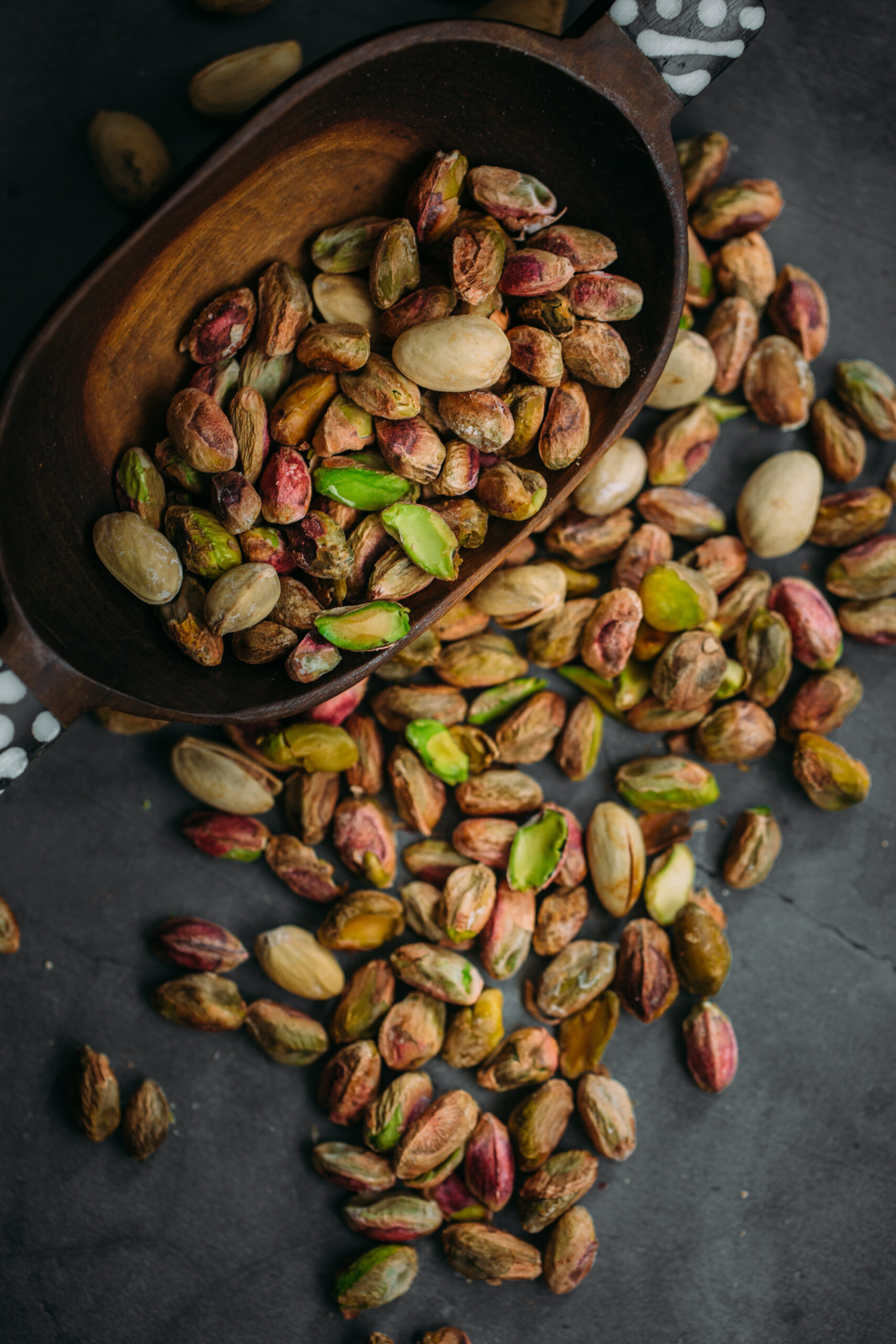Bowl with pistachios on a black table.